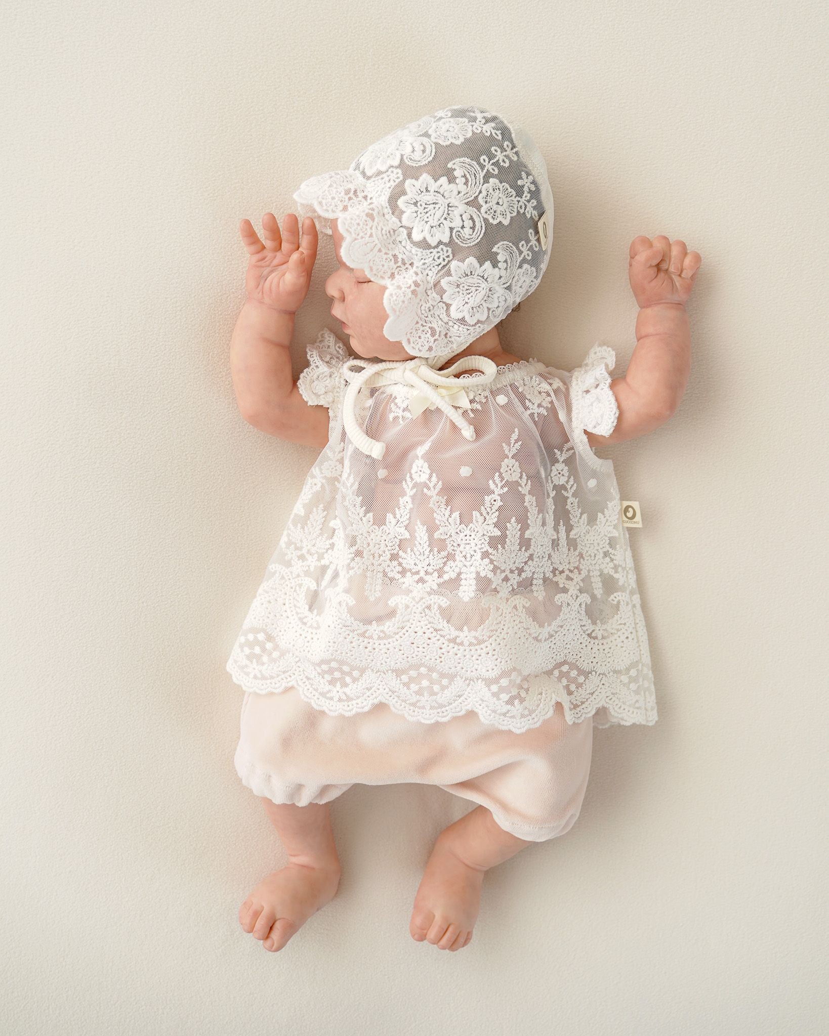 Neugeborenes Baby trägt ein festliches Kleid aus zarter Spitze