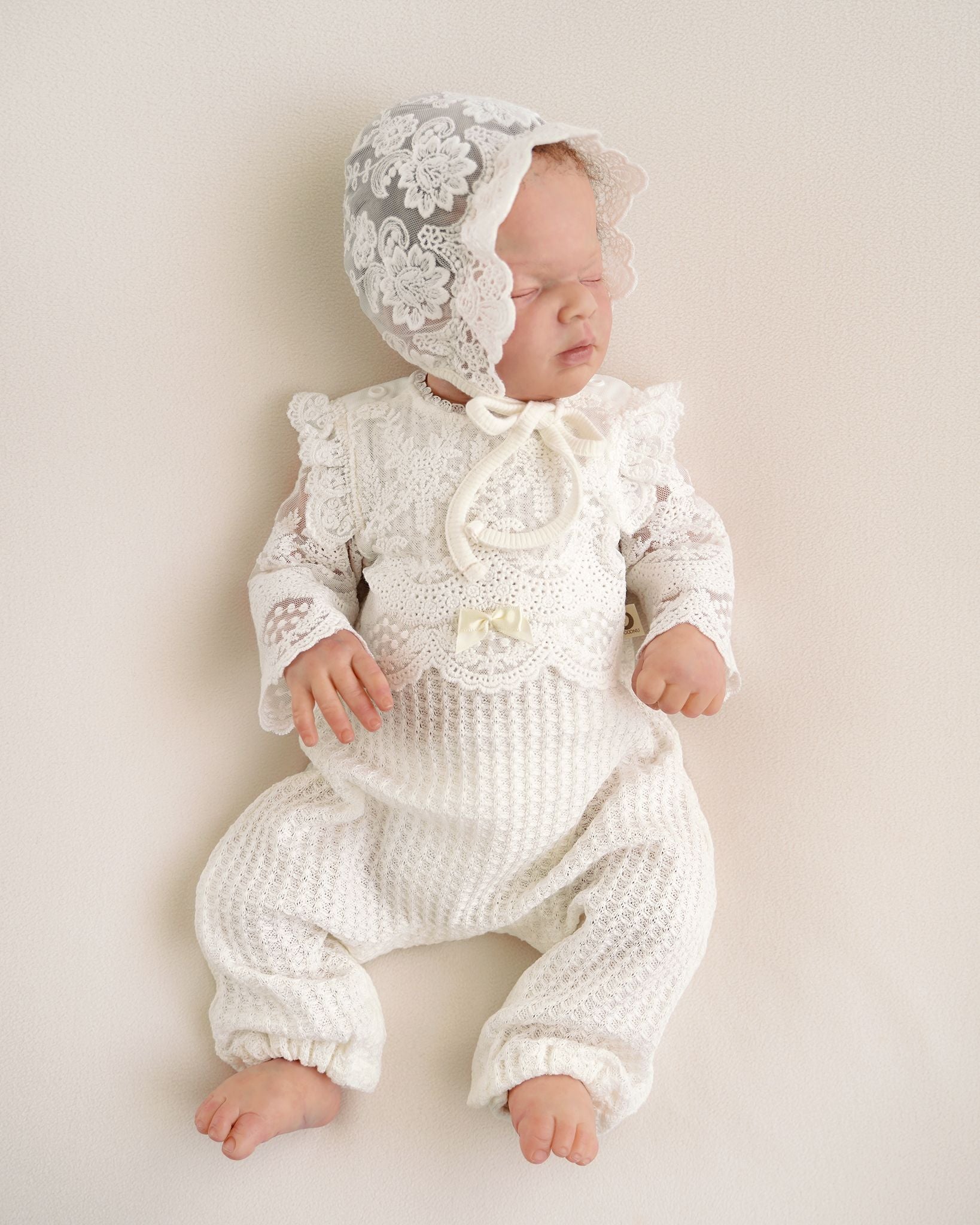 Neugeborenes Baby im festlichen CUCOONU Taufbody in Offwhite mit Spitze