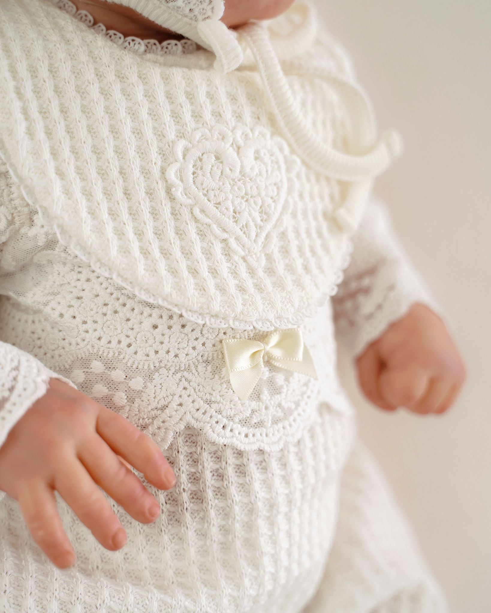 Festlicher CUCOONU Babybody in Offwhite, Detailaufnahme der Schleife auf der Spitze