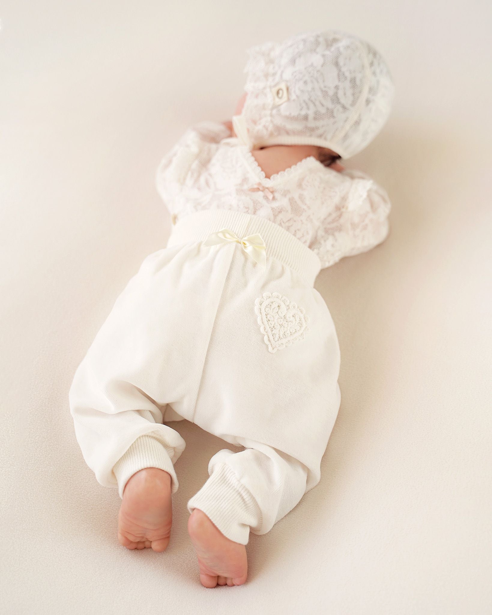 Rückenansicht einer CUCOONU Babyhose aus Samt in Offwhite mit Herzapplikation am Po