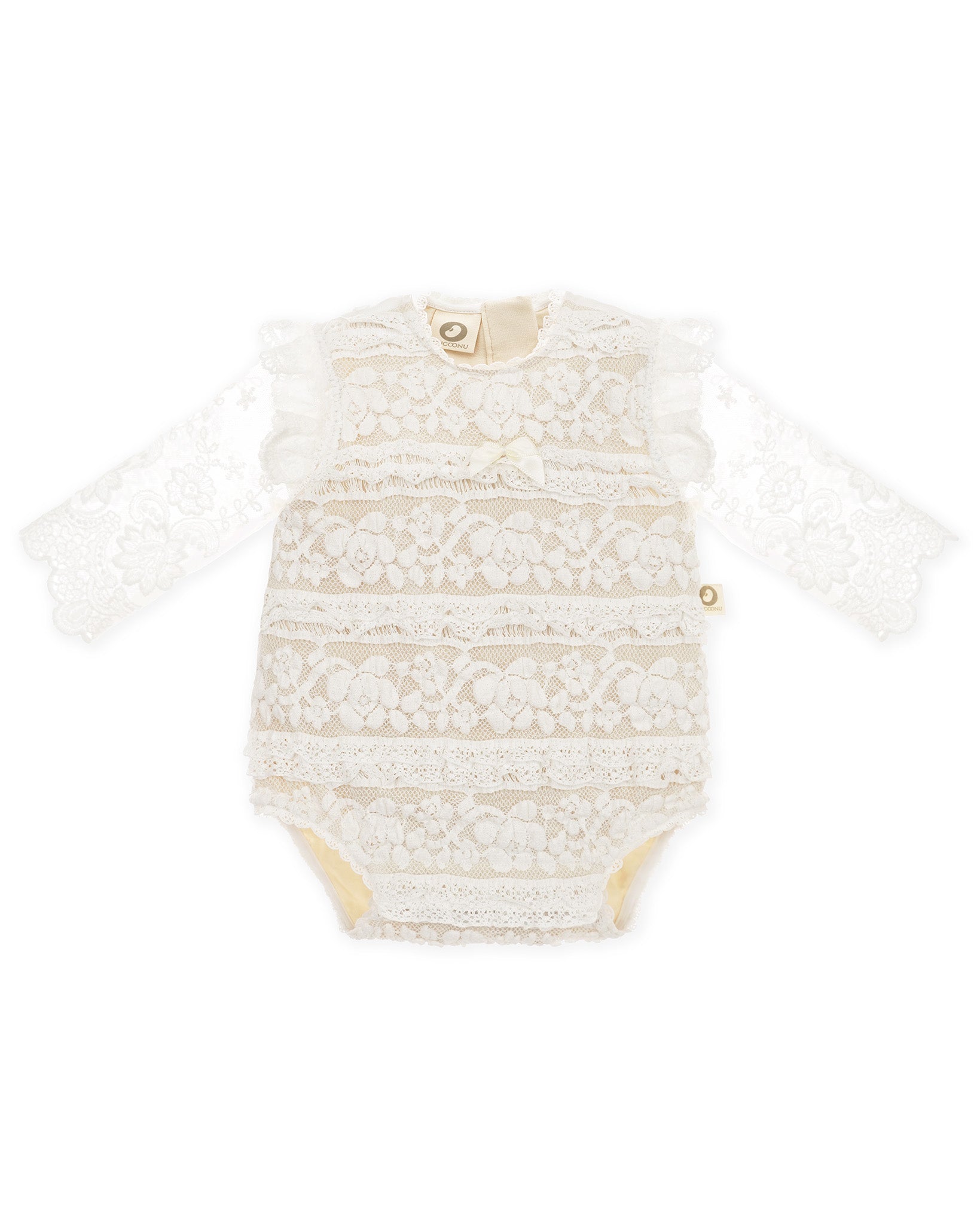 Vorderansicht eines festlichen CUCOONU Babybodys in Offwhite aus Spitze und kleinen Rüschen, hinterlegt mit beigefarbenem Jersey