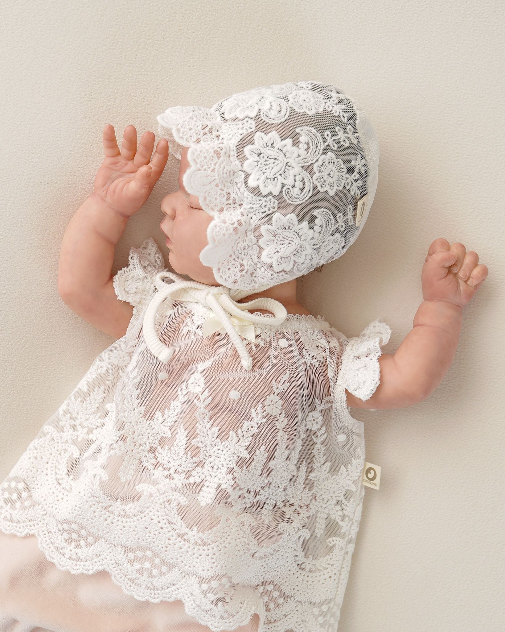 Baby mit festlichem Spitzenkleid und Taufmütze
