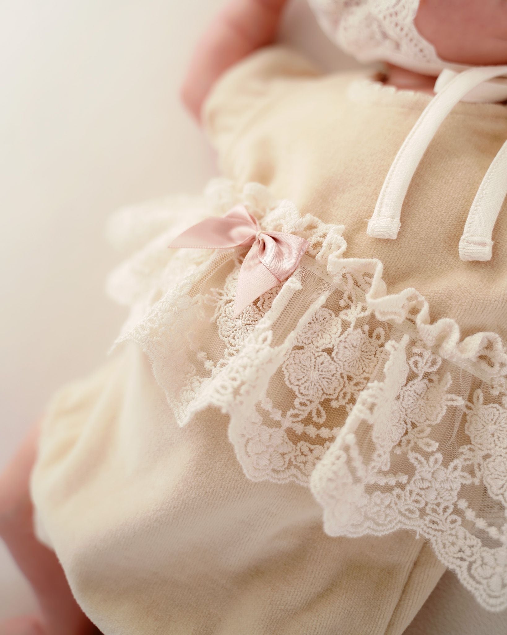 Detailaufnahme des festlichen CUCOONU Bodys in Beige: zarte Satinschleife auf Spitze