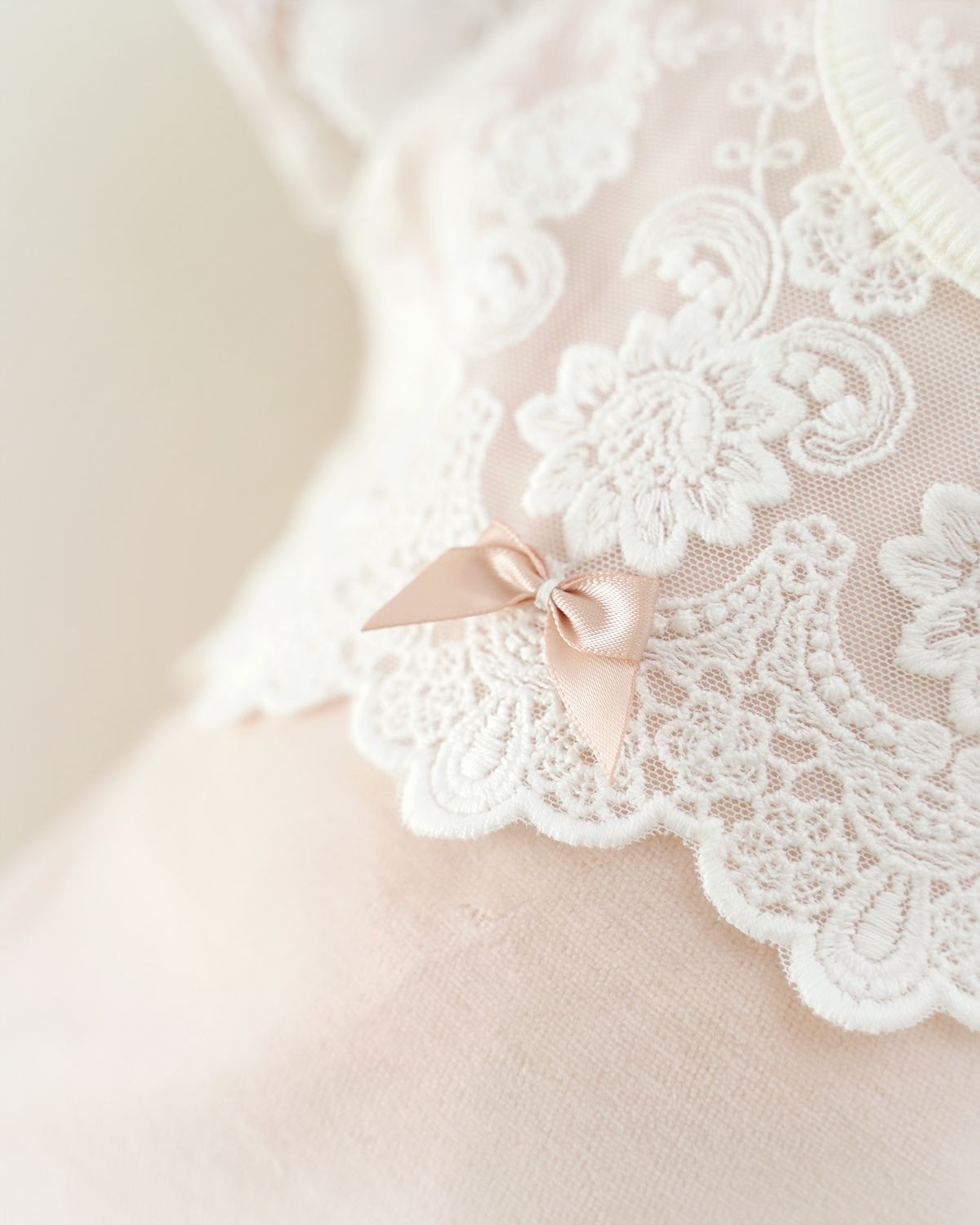 Festlicher CUCOONU Body in Rosa mit Detailaufnahme der rosafarbenen Satinschleife auf der Spitze in Offwhite