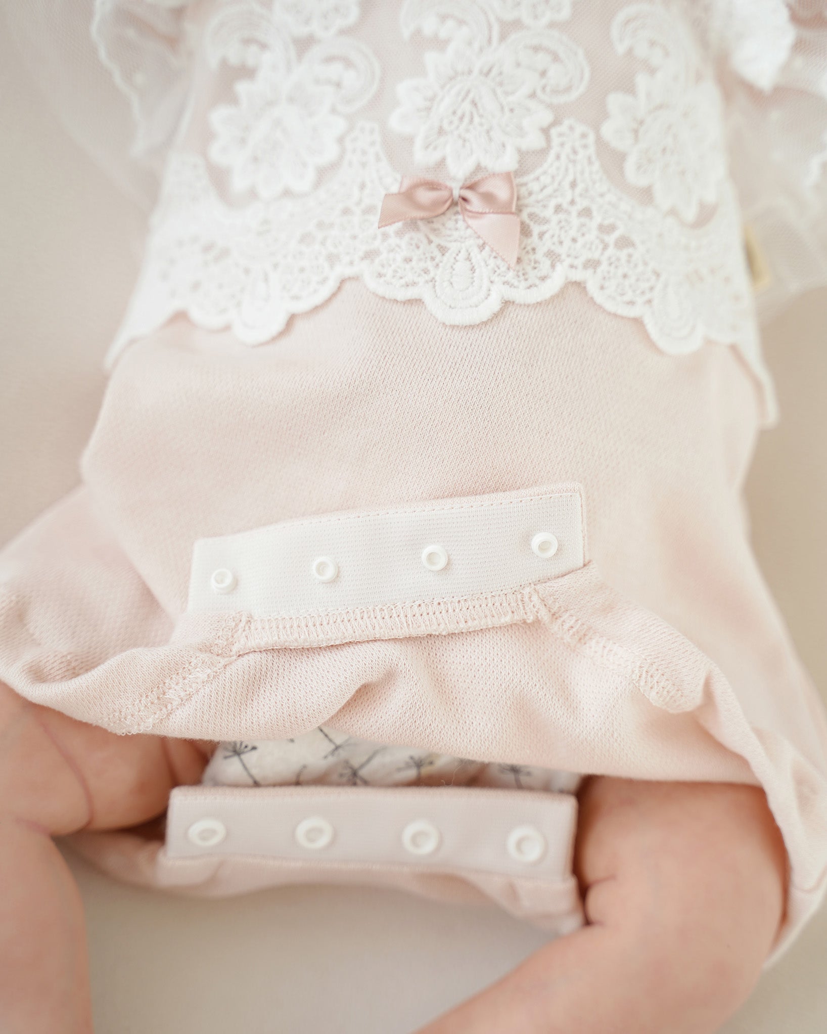 Detailaufnahme des Verschlusses im Schrittbereich des festlichen Babybodys in Rosa