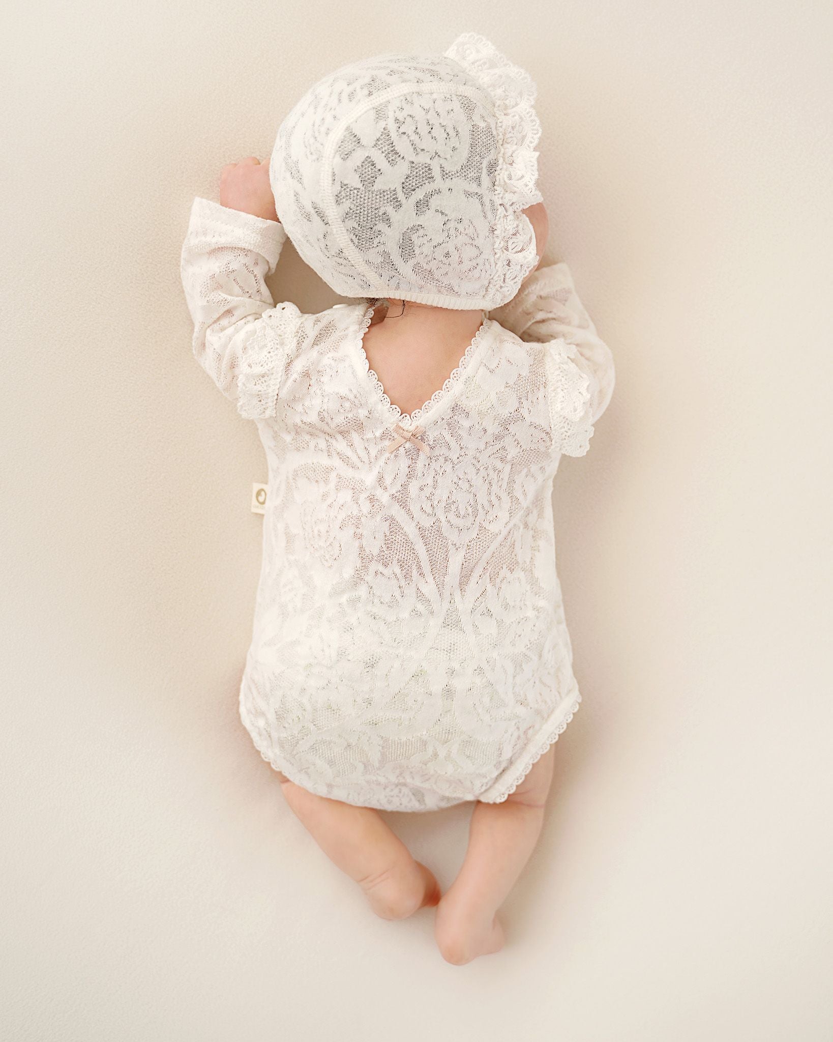 Rückenansicht eines festlichen CUCOONU Babybodys aus Seiden-Jersey-Jacquard in Offwhite mit V-Ausschnitt
