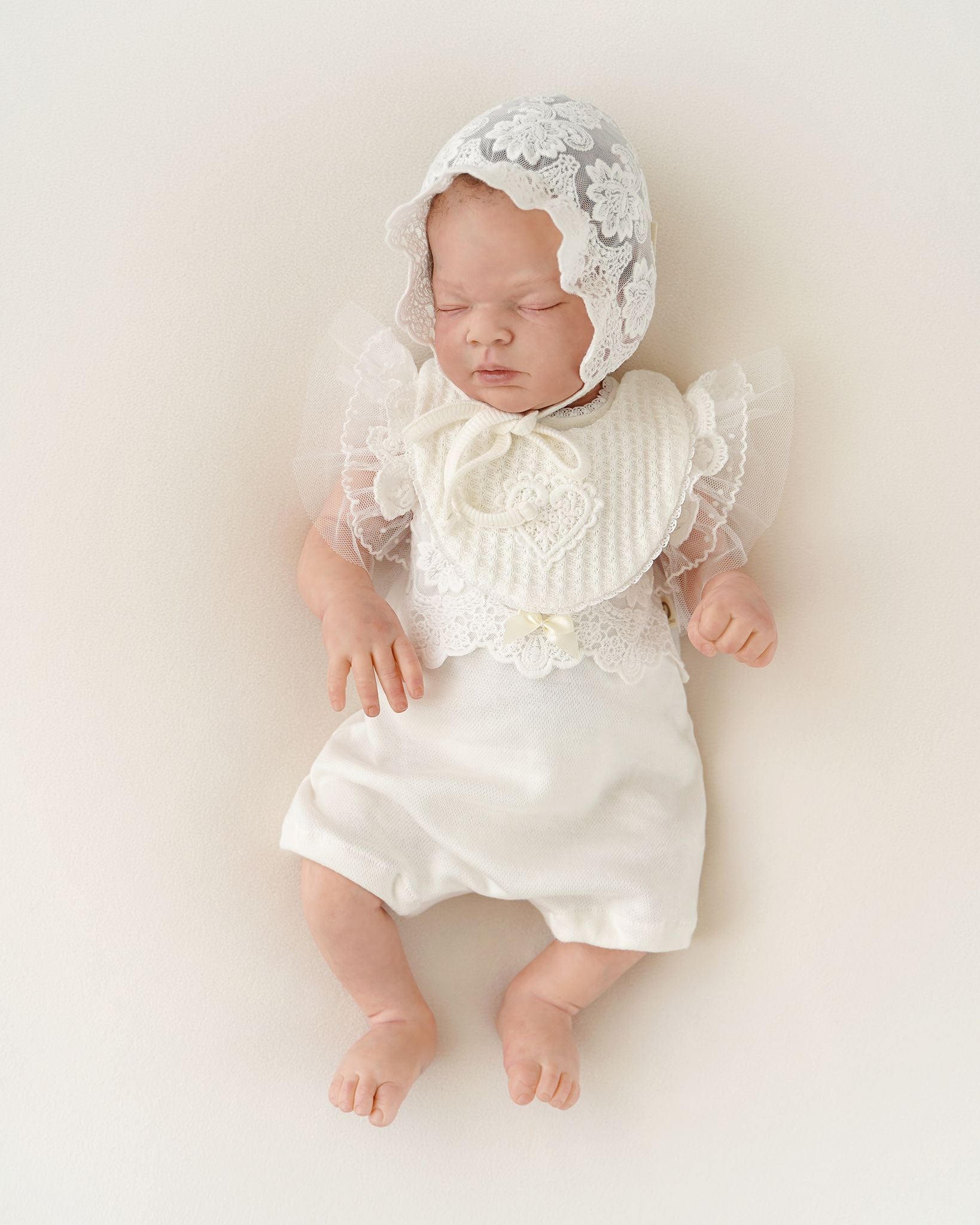 Baby trägt festlichen CUCOONU Body aus Pima-Baumwolle in Offwhite mit Tüllärmeln und Lätzchen mit Herzapplikation, Vorderansicht