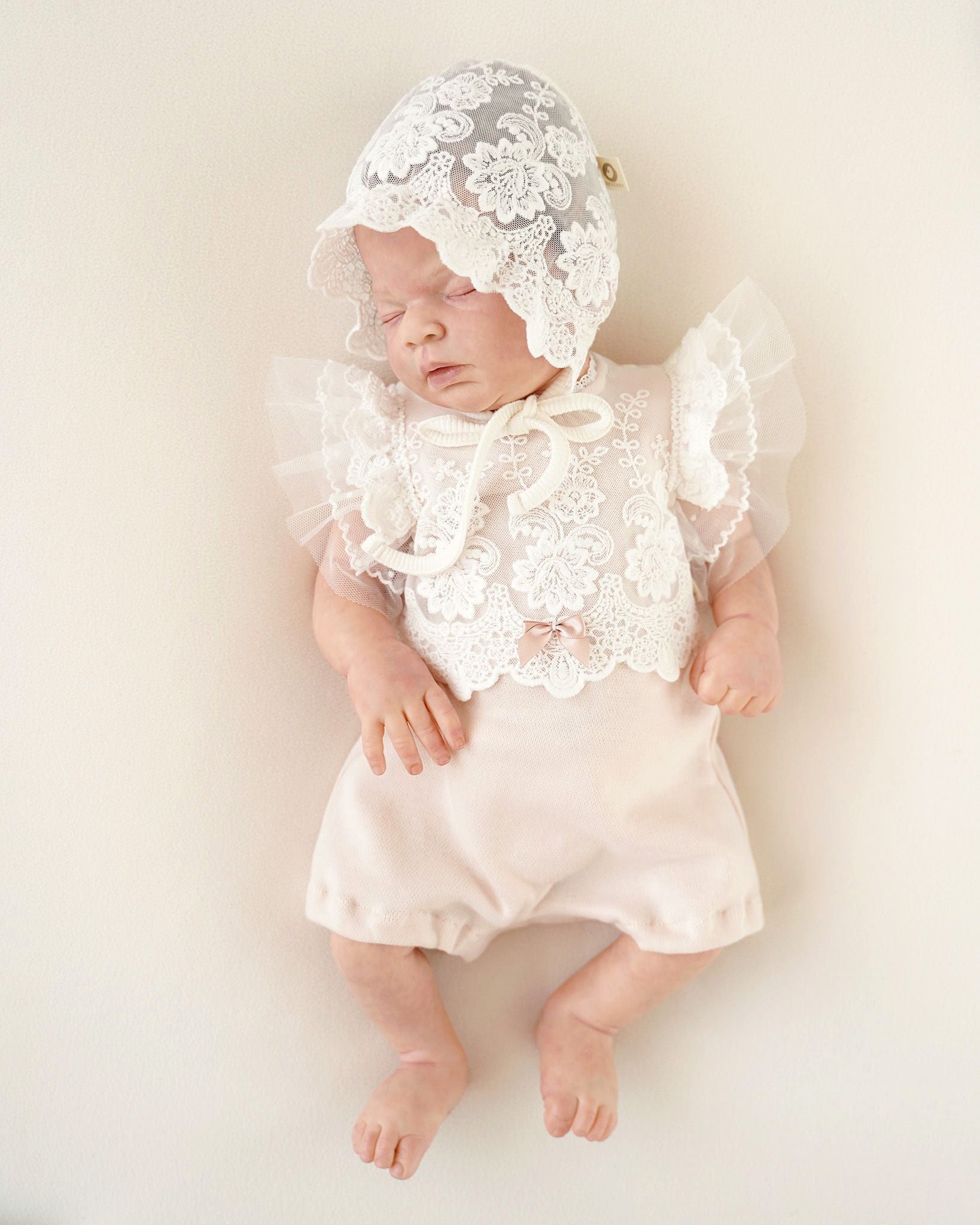 Baby trägt festlichen CUCOONU Body aus Pima-Baumwolle in Rosa mit Flügelärmeln in Offwhite, Vorderansicht