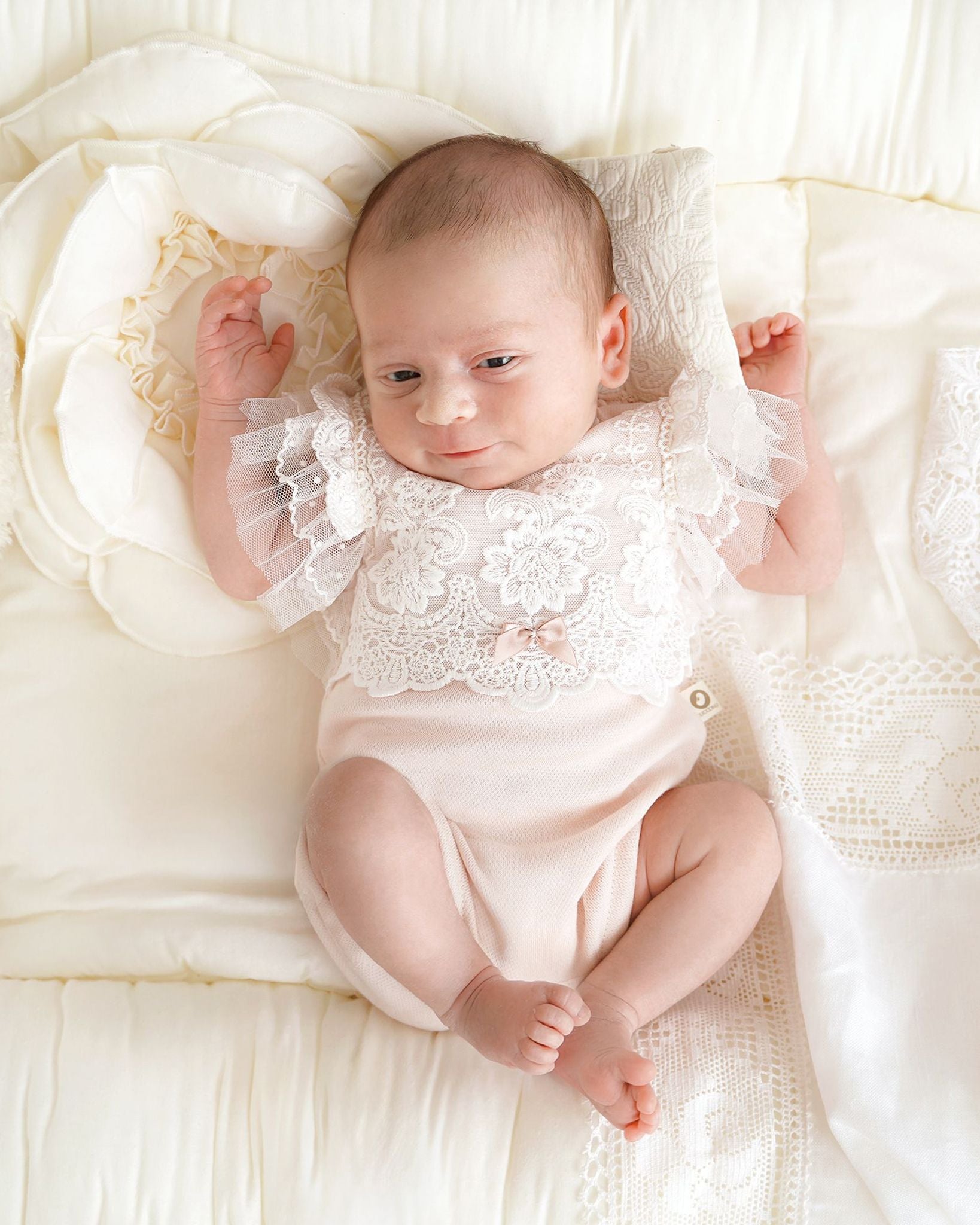 Baby trägt CUCOONU Taufbody in Rose mit Spitze