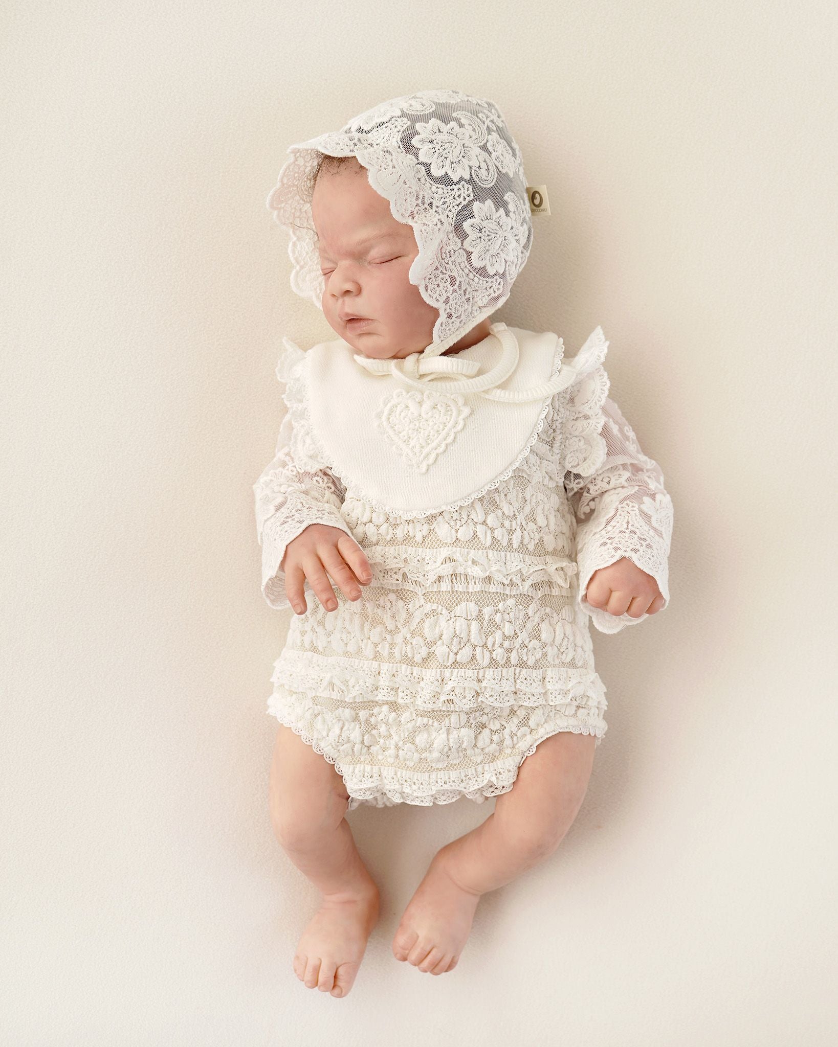 Baby in festlichem CUCOONU Babybody aus Spitze mit passendem Lätzchen in Offwhite