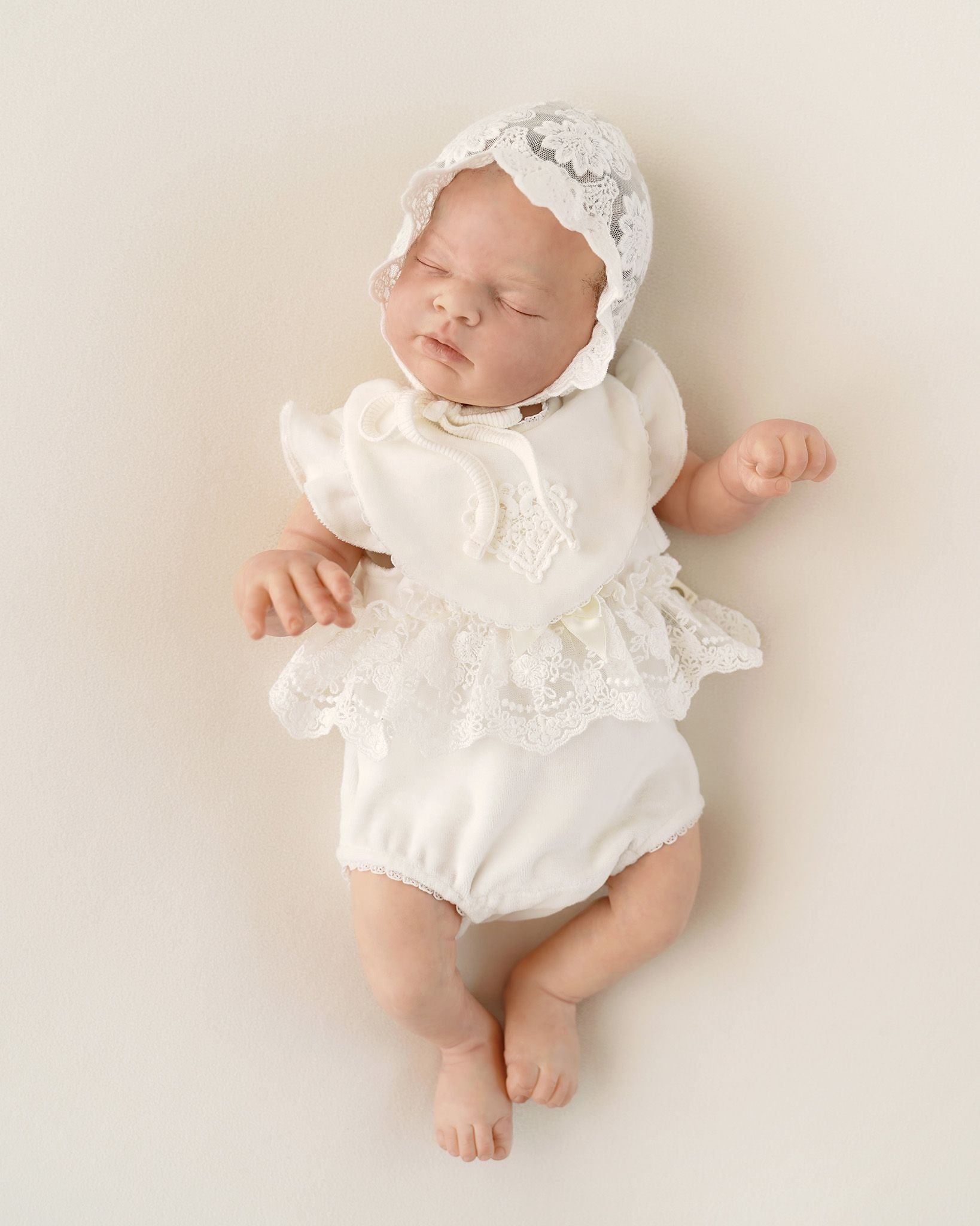 Baby trägt festlichen CUCOONU Body aus Samt in Offwhite mit Flügelärmeln, Rüschenborte vorne und Lätzchen mit Herzapplikation, Vorderansicht