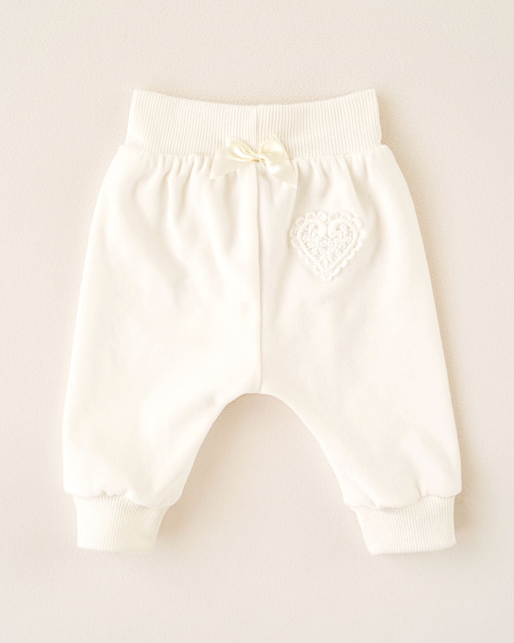 Rückenansicht einer CUCOONU Babyhose aus Samt in Offwhite mit Herzapplikation am Po und Schleife