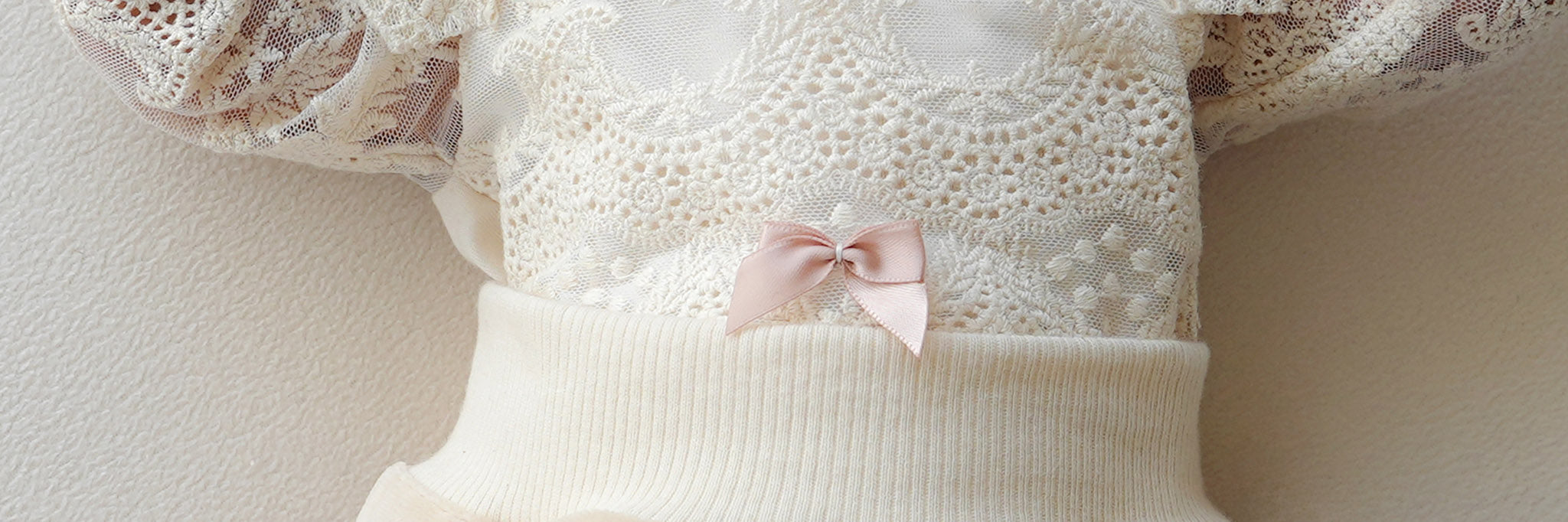 Zarte Satinschleife in Rosé auf edler Spitze, Detailaufnahme