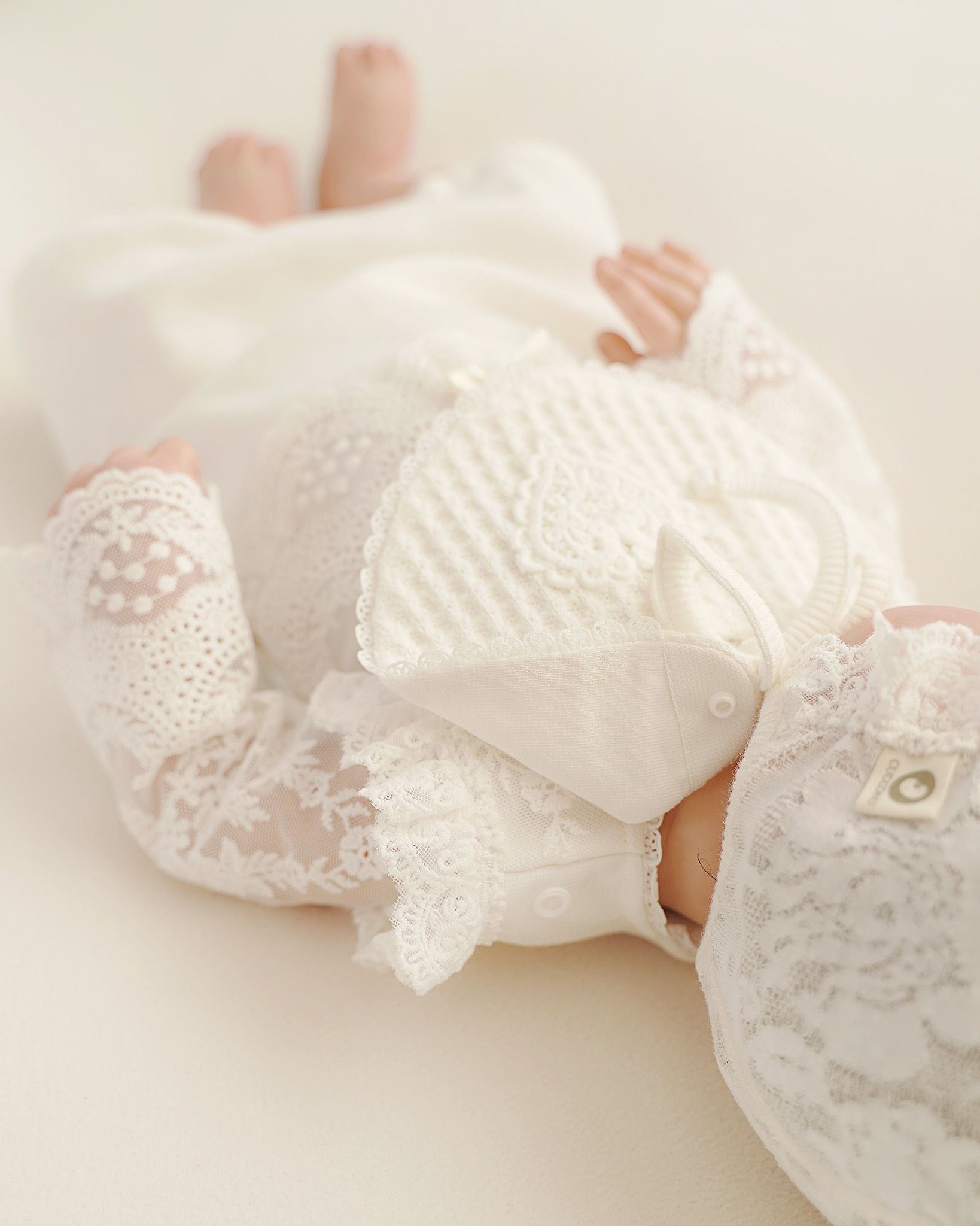 Detailaufnahme vom Lätzchenverschluss an festlichem Baby Taufkleid in Offwhite