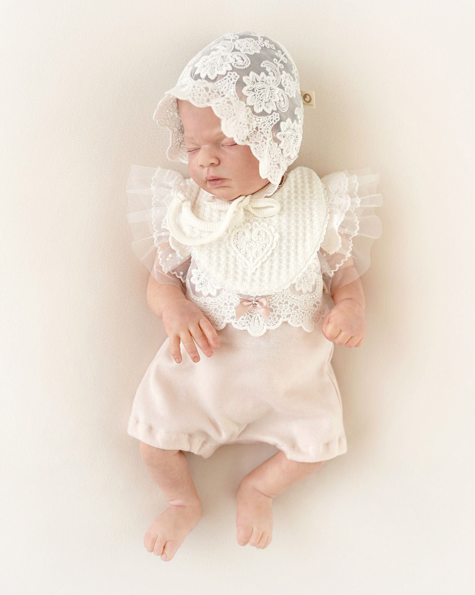 Vorderansicht eines festlichen CUCOONU Babybodys aus Samt in Rosa mit Tüllärmeln und Lätzchen mit Herzapplikation