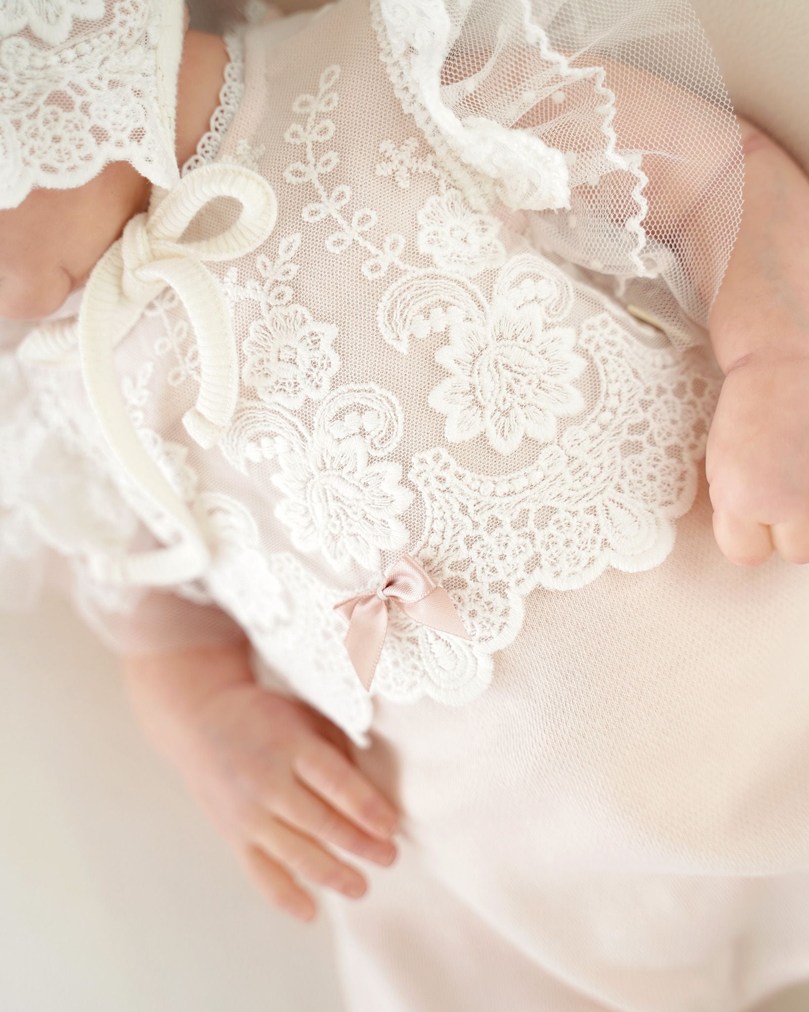 Detailaufnahme: Schleife auf der Spitze eines festlichen CUCOONU Babybodys in Rosa